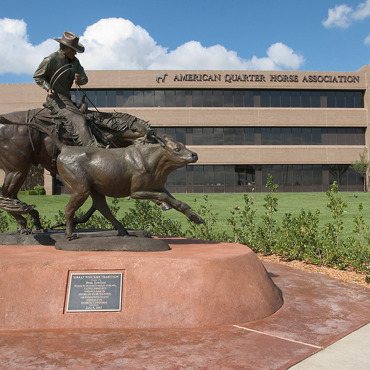 Statue of man on horse lassoing cow 